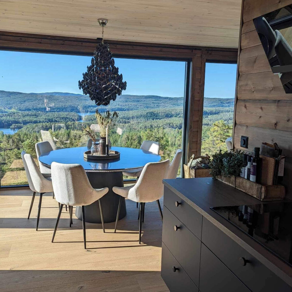 Utsikt fra Ørnerede. Spisegruppen er plassert framfor et stort vindu med panoramautsikt over landskapet.